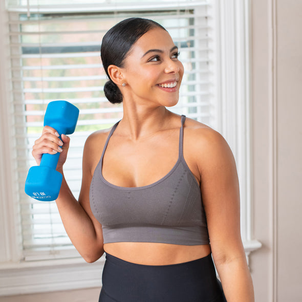 Femme effectuant un exercice de bras avec un haltère bleu de 10 livres recouvert de néoprène.