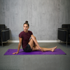 Femme s'étirant sur un tapis de yoga violet
