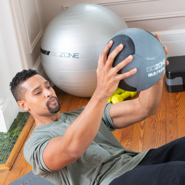 Man lying on back holding medicine ball in out in front of him