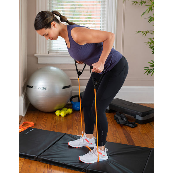 Woman working out with resistance and tube on black fitness mat