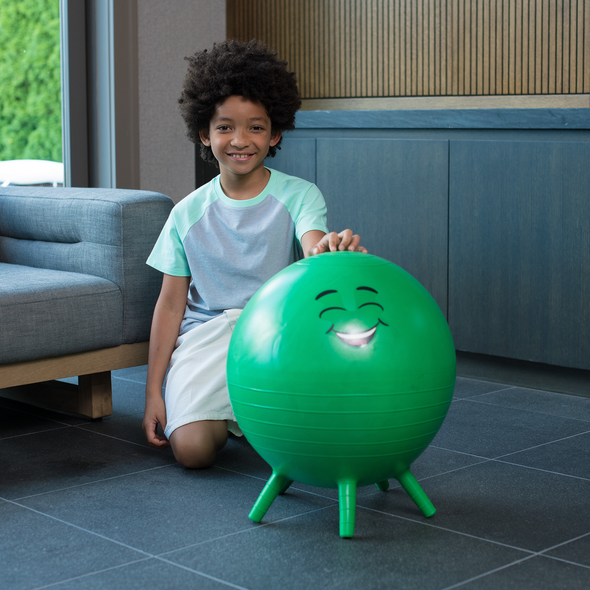 Kid kneeling next to green Stay and Play fitness ball